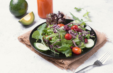 Fresh healthy vegetable salad with tomato, cucumber, spinach, lettuce in plate on table background.