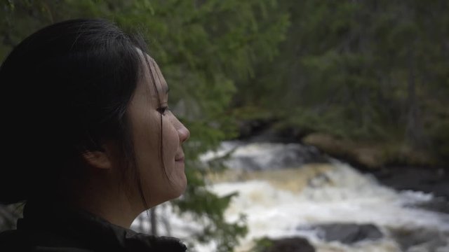 Girl looking at a river in the forest.