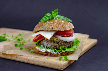 burger with homemade whole grain bun, beef cutlet, tomatoes, onion, salad, mozzarella, yogurt and mustard. healthy food. proper nutrition fast food