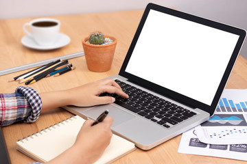 online learning course concept. student using computer laptop with white blank screen for training online and writing lecture note in notebook. distance education