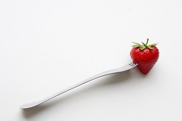 Fresh strawberries on a fork on a white background.