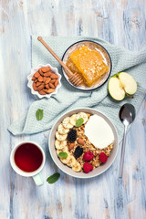 Healthy breakfast with granola, berries, honeycombs  and yogurt and a cup of tea