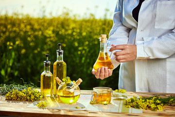 rapeseed oil bottle in hand of an agronomist or biologist on background rape field