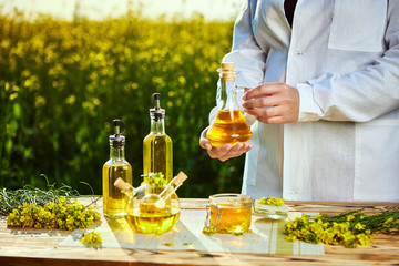 rapeseed oil bottle in hand of an agronomist or biologist on background rape field