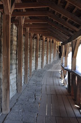 A long corridor of stone and wood. Arcade of wooden piles.