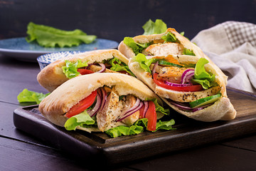 Pita stuffed with chicken, tomato and lettuce on wooden background. Middle Eastern cuisine.
