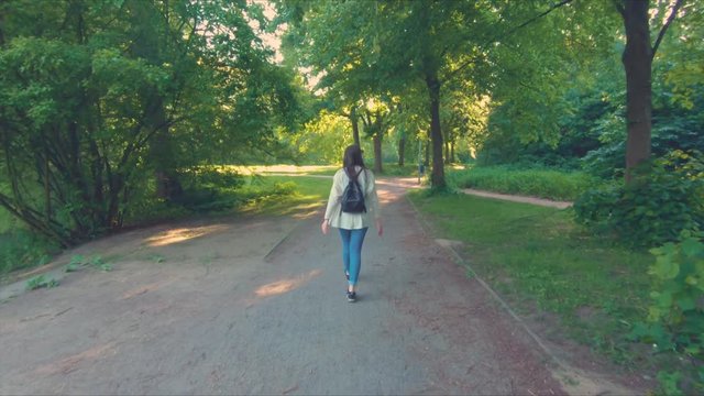 Young Woman Walking Through A Park With Swinging Arms At A Sunny Day