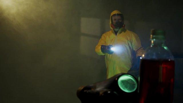 Hazmat suit wearing man explores a dark room