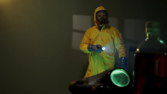 Hazmat suit wearing man explores a dark room