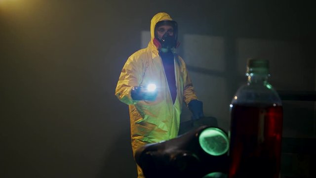 Hazmat suit wearing man explores a dark room