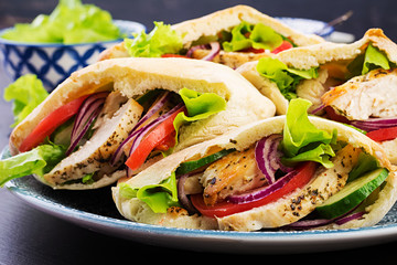Pita stuffed with chicken, tomato and lettuce on wooden background. Middle Eastern cuisine.