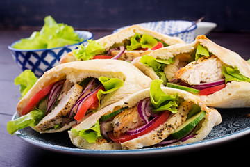 Pita stuffed with chicken, tomato and lettuce on wooden background. Middle Eastern cuisine.
