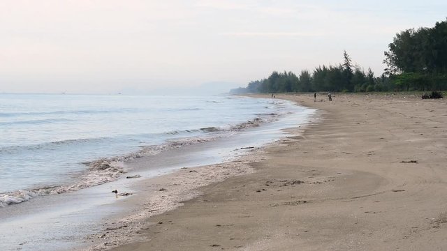 Real time footage of a tropical beach in Kelantan, Malaysia with unrecognized people having fun playing with waves
