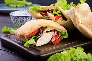 Pita stuffed with chicken, tomato and lettuce on wooden background. Middle Eastern cuisine.