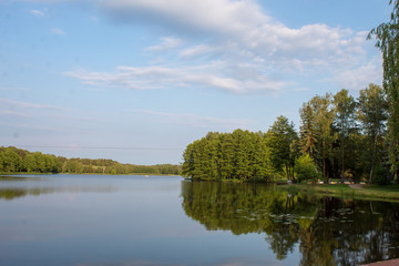 Obraz premium Landscape of a beautiful superficial blue lake surrounded by forest in the central part of Poland on a sunny summer day.