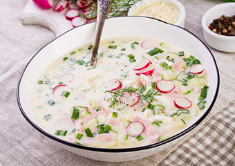 Cold soup with fresh cucumbers, radishes, potato and sausage with yoghurt in bowl. Traditional russian food - okroshka. Summer cold soup.
