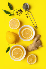 Ginger lemon tea or detox drink in a white cup on a bright yellow background. Healthy eating concept. Vertical frame.