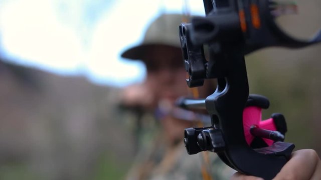 Woman aiming at a target and preparing to shoot a bow and arrow.