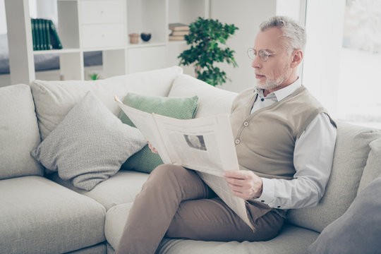 Close up side profile photo amazing he him his aged man arms hands look fresh newspaper political media wear specs white shirt waistcoat pants sit cosy comfort bright flat house living room indoors