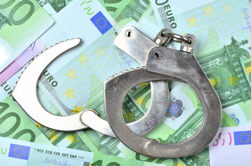 View from above of police handcuffs on euro banknotes - finance and criminality concept