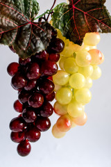bunch of red and green grapes with leaves isolated on white
