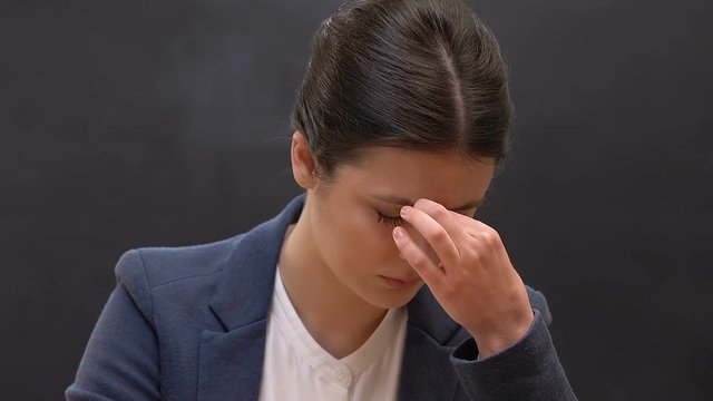 Tired female teacher taking off eyeglasses and massaging nose, overworking