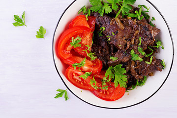 Roasted or grilled beef liver with onion and tomatoes salad. Middle Eastern cuisine. Top view