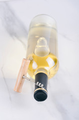 Vertical shot.Sealed bottle of wine and corkscrew on the bright surface 