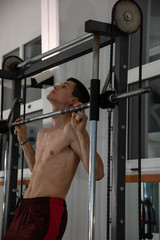 Fototapeta na wymiar The young male exercises in the gym uses the multipower. Concept of fitness, sport, training, gym and lifestyle.