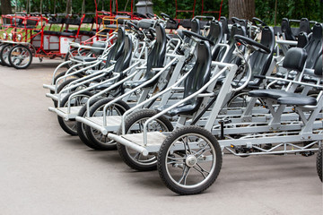 Fototapeta na wymiar Bicycles for rent steel black pedal. Parked rental tourist trike vehicles velomobiles. Ecological urban transport