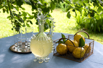 Homemade lemonade in a vintage carafe with lemons.