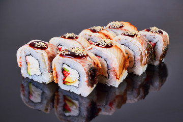 Philadelphia roll sushi with smoked eel, avocado, tuna and cream cheese on black background for menu. Japanese food