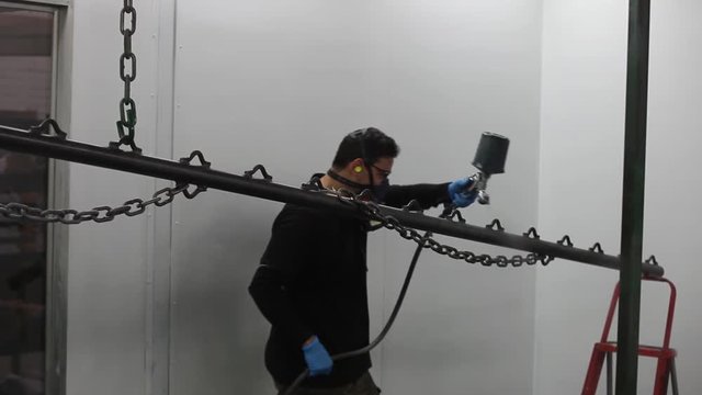 Professional air brusher working in a spray booth on metal parts 3