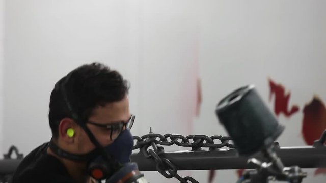 Professional air brusher working in a factory on metal parts 4