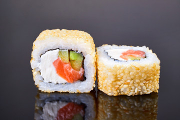 California roll sushi with sesame, salmon, avocado and cream cheese on black background for menu. Japanese food