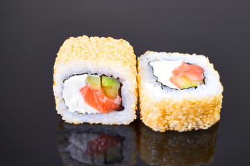 California roll sushi with sesame, salmon, avocado and cream cheese on black background for menu. Japanese food