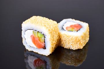 California roll sushi with sesame, salmon, avocado and cream cheese on black background for menu. Japanese food