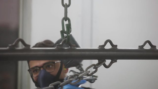 Professional air brusher working in a spray booth on metal parts 1