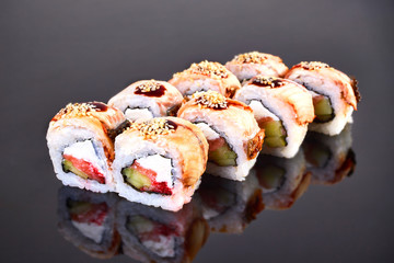 Philadelphia roll sushi with smoked eel, avocado, tuna and cream cheese on black background for menu. Japanese food