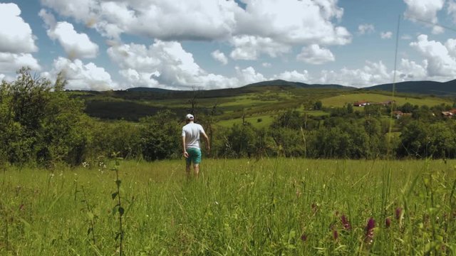 Traveler walking through a green field.