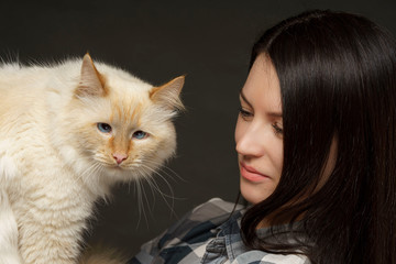 A girl with a big beige cross-eyed cat in her arms