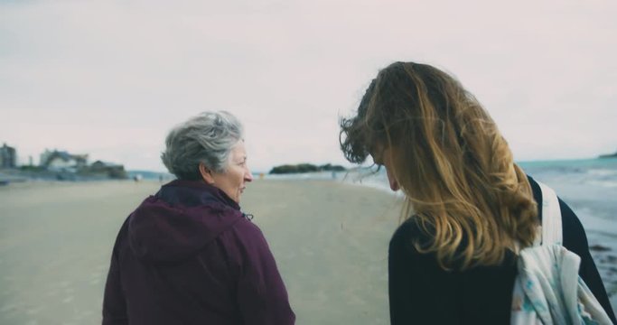 Young  woman walking on the beach with her mother