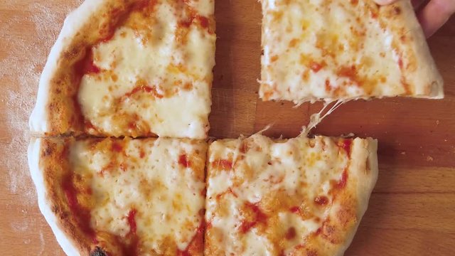 Prendere un quarto di spicchio di pizza margherita rotonda cotta nel forno a legna, da un tagliere in cucina.