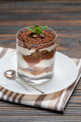 Classic tiramisu dessert in a glass on wooden background