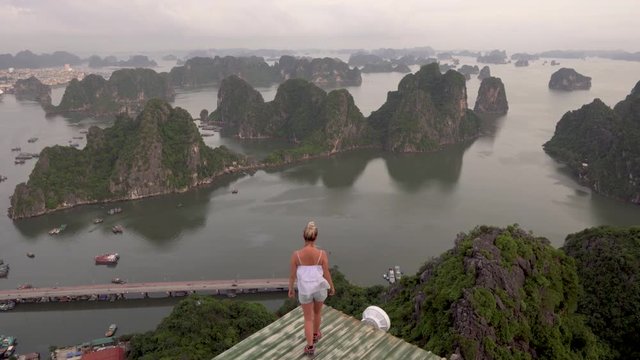 Blonde tourist girl looking at the spectacular Ha Long Bay from Poem Mountain viewpoint in Vietnam