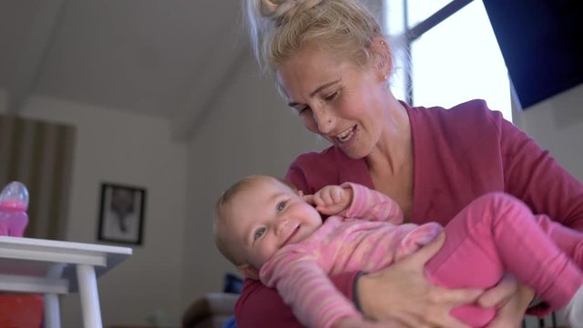Slow motion shot of a young mother gently rocking her baby daughter back and forth in her arms