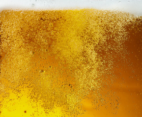 Close up view of floating bubbles in light golden colored beer background. Texture of cooling...