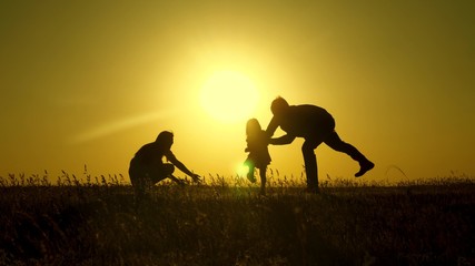 parents play with their little daughter. mother and Dad play with their daughter in sun. happy baby goes from dad to mom. young family in field with a child 1 year. family happiness concept.