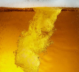 Close up view of floating bubbles in light golden colored beer background. Texture of cooling...
