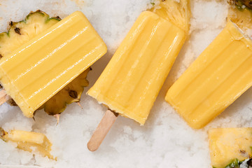 Yellow fruit popsicles on a tray top view, summer mood